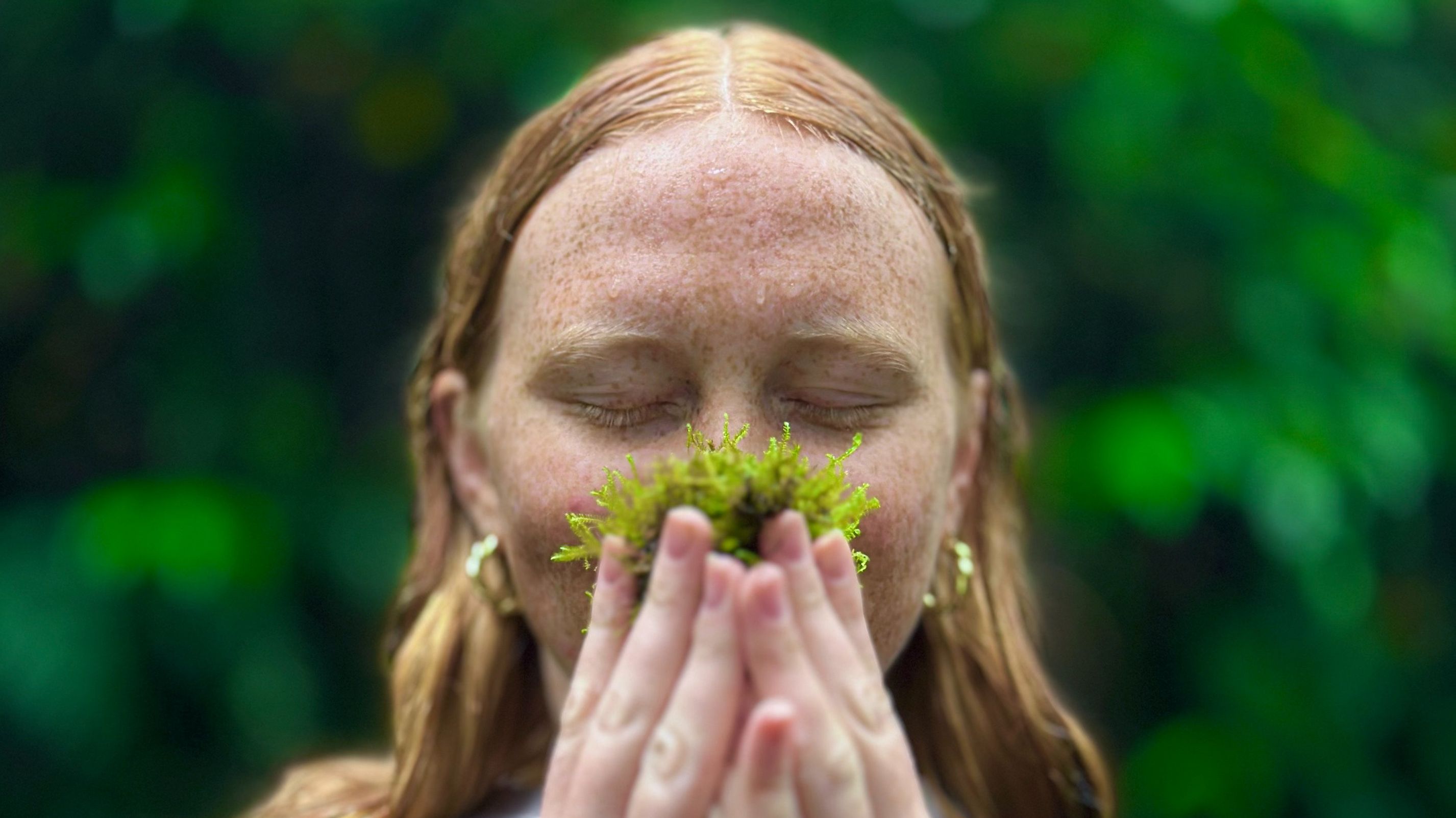 Woman enjoying the scent of nature in Monteverde’s cloud forest, surrounded by lush greenery.
