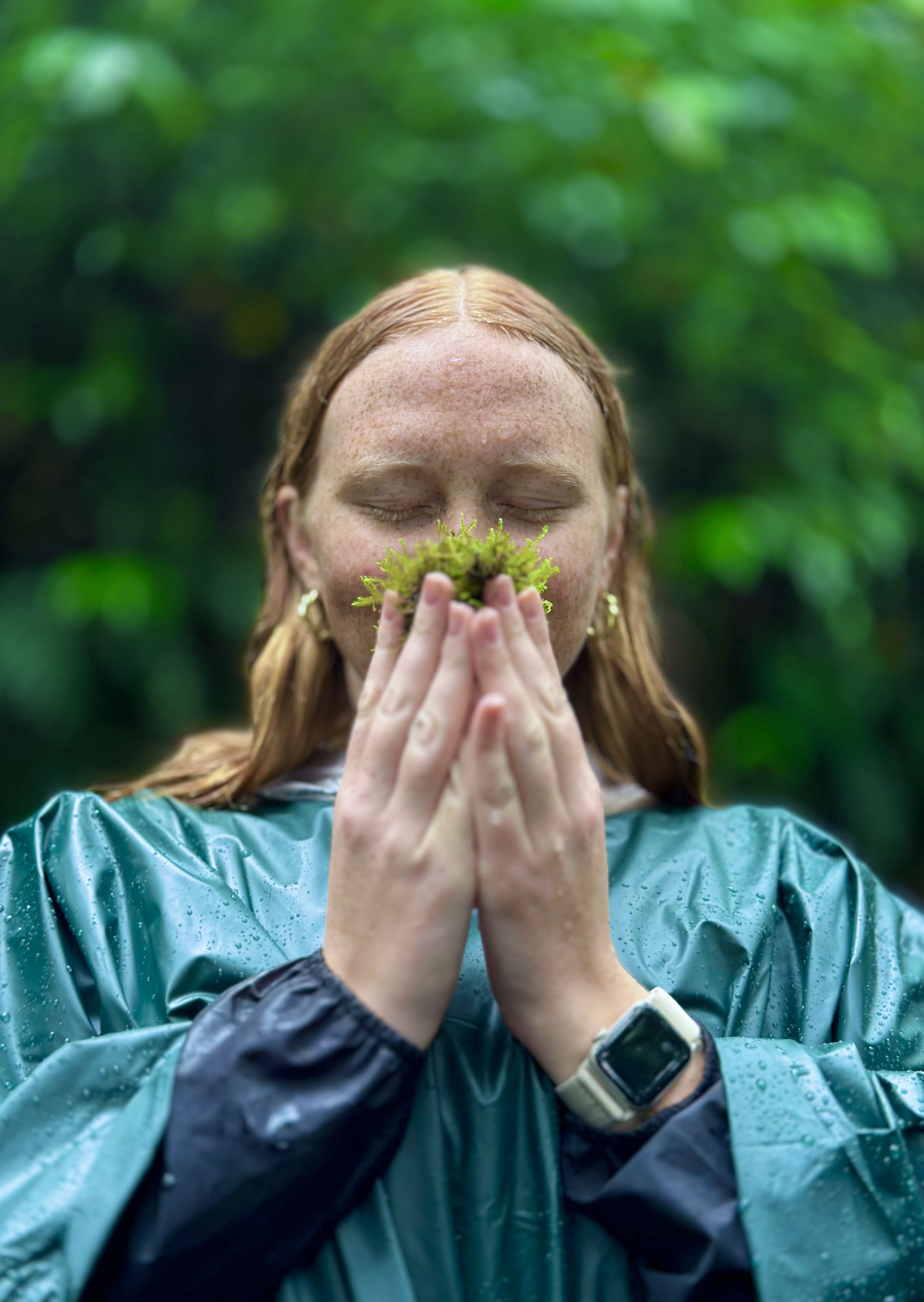 Person holding and smelling a bunch of moss in the cloud forest of Monteverde, Costa Rica.