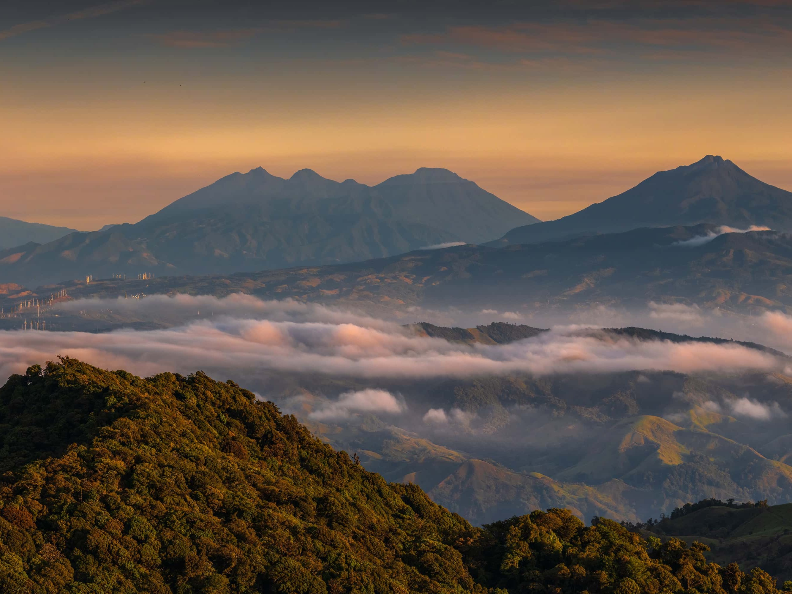 Panoramic view of Monteverde’s mountainous landscape with cloud banks and warm light at sunrise or sunset
