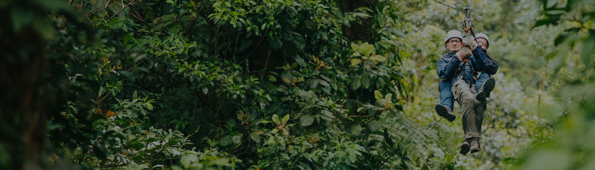 Two people ziplining on a canopy tour in Monteverde, Costa Rica, with lush green forest in the background