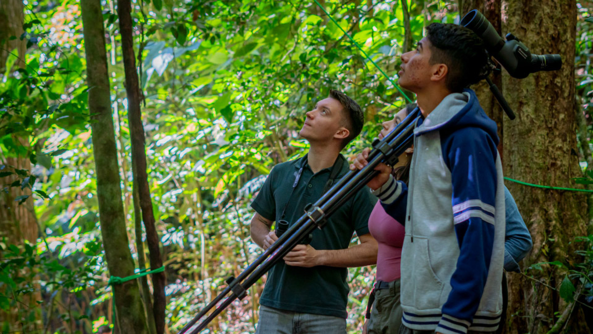 Guide with two tourists on a forest trail carrying a tripod telescope during the Natural History Forest Walk tour at Finca Lantana, Monteverde, Costa Rica